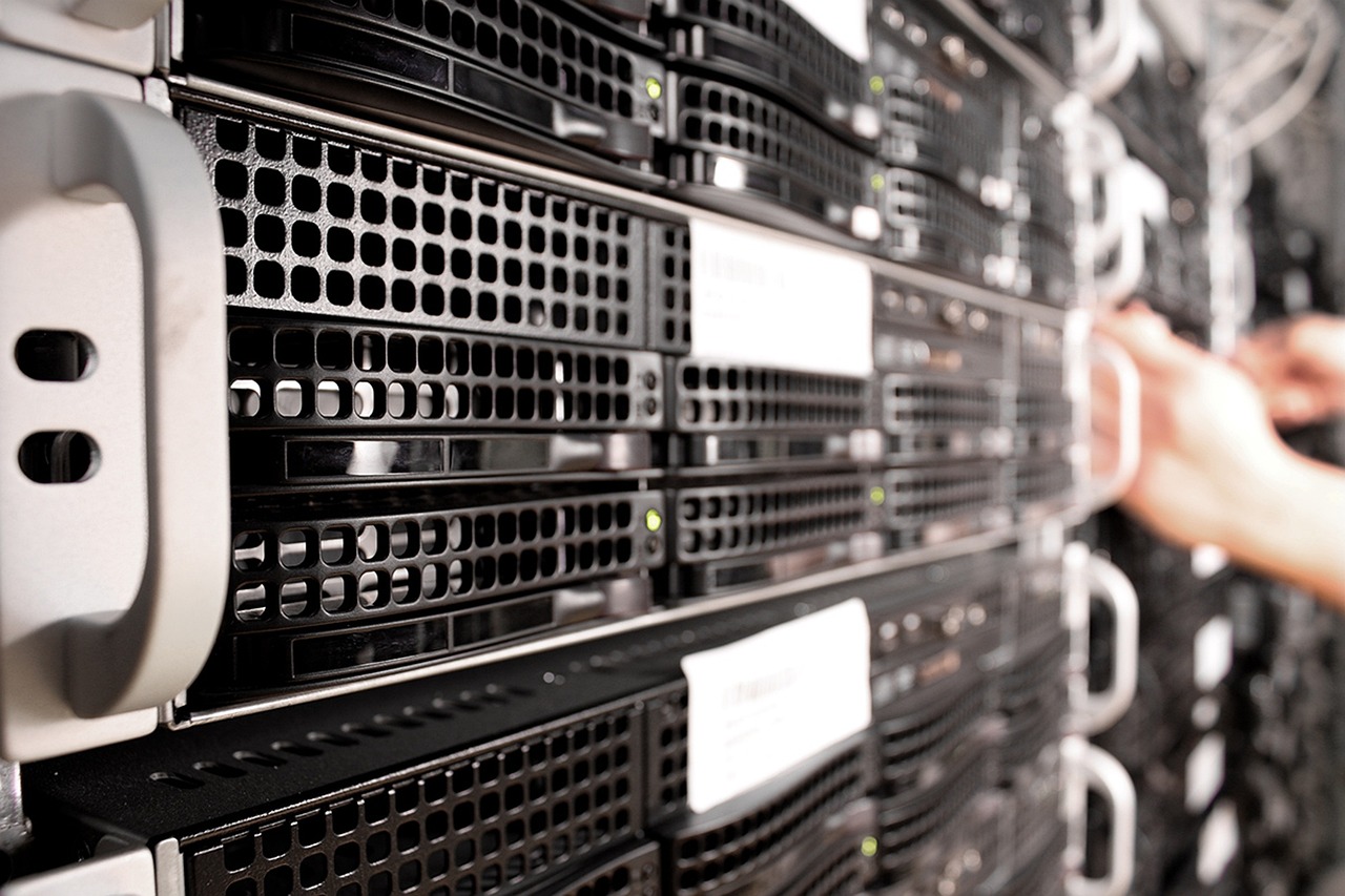 Rack-mounted servers in a data centre with a hand reaching toward a unit