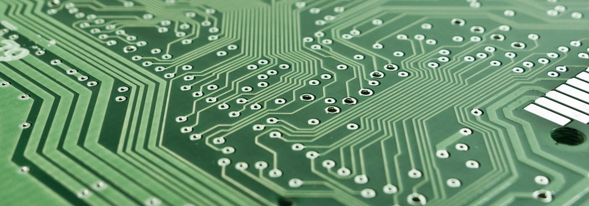 A close-up of a green printed circuit board with electronic components