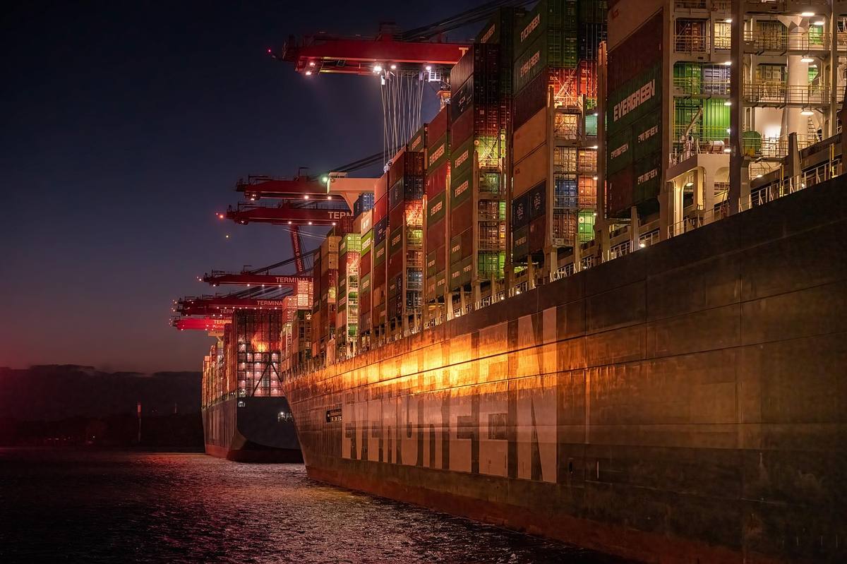 A container ship loaded with stacked shipping containers at a port at night